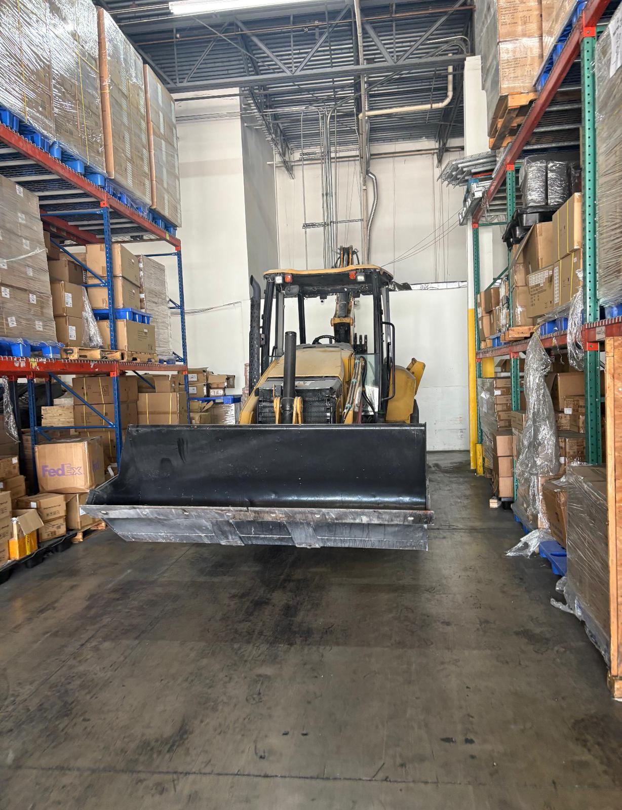 CAT backhoe loader staged in a warehouse before transport