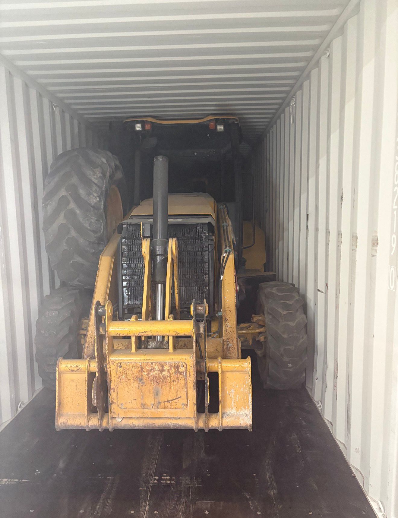 CAT backhoe loader disassembled and packed inside a standard shipping container for export